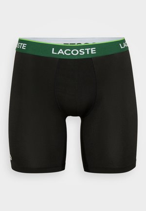 Zwarte boxer shorts van lichtgewicht stof. Voorzien van een groene en witte merk-elastische tailleband. Soepele textuur, aansluitend ontwerp.