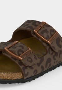 Καφέ σανδάλι Birkenstock με λεοπάρ σχέδιο, δύο ρυθμιζόμενες χαλκές αγκράφες και φιάπα από φελλό σε μαύρη σόλα, κοντινή άποψη.