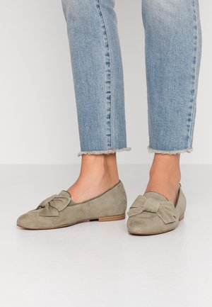 Zachte grijs-groene suède ballerina's met een strikdetail op de neus. Lage gestapelde hak en een rond neusontwerp. Gekozen in combinatie met jeans met franjes.