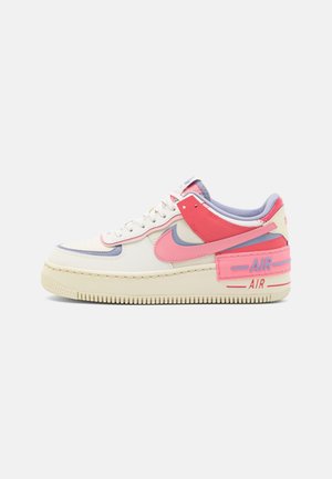 Basket basse Nike Air Force 1 crème, rose et violette avec le logo "AIR" visible sur le panneau du talon de la semelle intermédiaire.