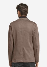 Brun, texturerad jacka med långa ärmar och krage, med en söm bak och sidofickor. Enkelt mönster med neutral färgschema.