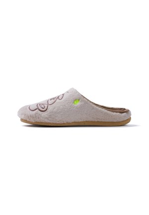 Zapatilla beige suave tipo slip-on con suela marrón, textura peluda, remolino decorativo marrón en la parte superior y pequeño detalle de pez amarillo-verde en el lateral.