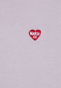 Svijetloplavi pleteni materijal s malim crvenim srcem kao logom, uz bijelu izvezenu natpis "MAKIA CO." kao detalj brendiranja.