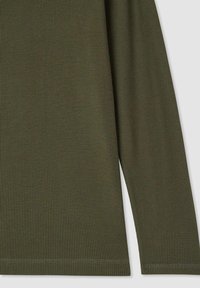 Maglia a maniche lunghe di colore verde oliva in maglia waffle, dettagli ravvicinati delle maniche e del lato, che mostrano il tessuto texturizzato e l'orlo piegato.