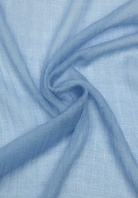 Miękka, jasnoniebieska przezroczysta tkanina o luźnym splocie, skręcona w delikatny spiralny wzór.