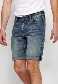 Denim shorts in a light blue wash with a rolled hem. Features include standard pockets and contrast stitching for added detail.