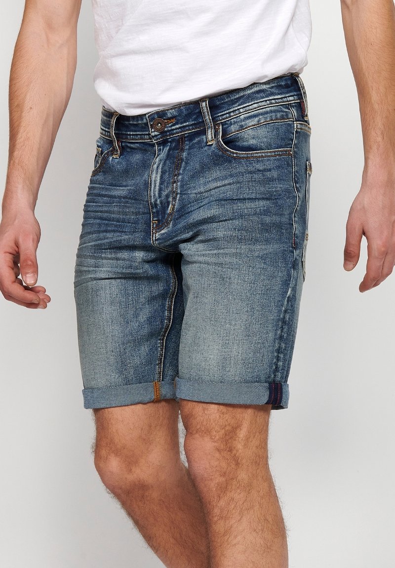 Denim shorts in a light blue wash with a rolled hem. Features include standard pockets and contrast stitching for added detail.