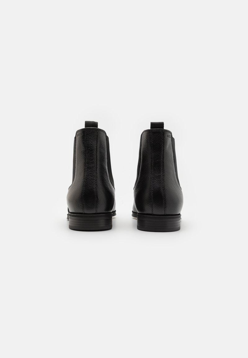 Bottines en cuir noir avec surface texturée, panneaux latéraux élastiques et petite languette à l'arrière. Talon bas empilé.