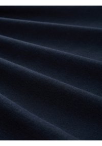 Tessuto blu navy con una superficie liscia e tessurizzata, caratterizzato da pieghe sottili e una trama densa, mostrato da vicino per evidenziare i dettagli.