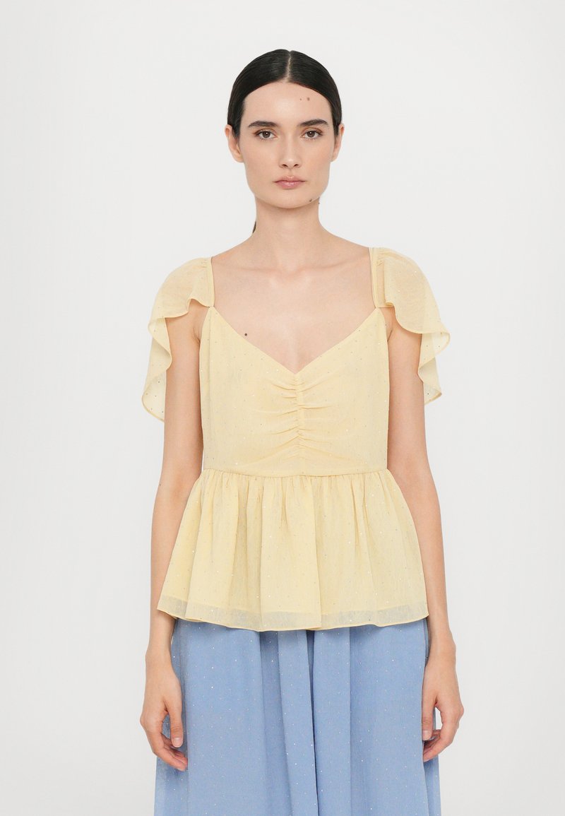 Gelbe Peplum-Bluse mit kurzen, gerafften Ärmeln, gerafftem Oberteil und weicher Textur. Kombiniert mit einem hellblauen Stoff darunter.