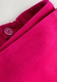 Fuchsia ribbed fabric with a fold-over collar and a clear button accent near the neckline. Soft texture, emphasizing the vibrant color.