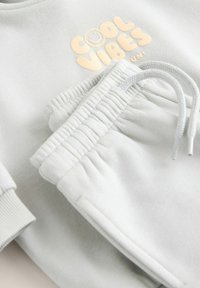 Hellgrau Sweatshirt und Sweatpants Set, featuring ein "Cool Vibes" Grafik in sanftem Gelb, mit gerippten Bündchen und Bund, glatte Textur.