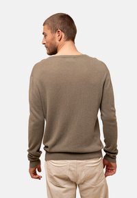 Khakifarbenes Sweatshirt aus weichem Strickstoff, mit Rundhalsausschnitt und gerippten Bündchen. Kombiniert mit hellbeigen Hosen. Rückansicht angezeigt.
