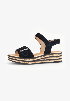 Black suede wedge sandals featuring two wide straps, a metallic buckle accent, and a layered cork platform sole.