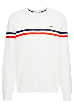 Biały sweter z okrągłym dekoltem z granatowymi i czerwonymi poziomymi paskami na klatce piersiowej i rękawach, z małym zielonym logo krokodyla na lewej stronie klatki piersiowej.