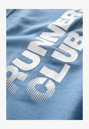 Tissu en coton bleu clair avec un texte blanc audacieux au design rayé. Le texte indique "CLUB DES COUREURS". Texture lisse avec finition mate.