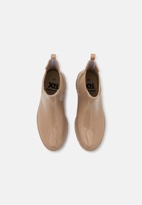 Botas de tobillo marrón claro, hechas de un material brillante, con una lengüeta, punta redondeada y suela de goma texturada para mayor agarre. Talla 37.