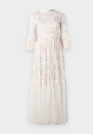 Vestido maxi feito de tecido branco transparente, com bordados florais em rosa e azul, mangas bufantes e camadas de babados na barra.