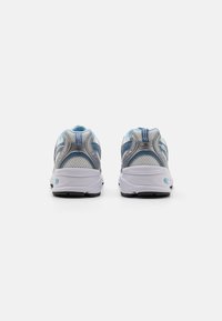 Scarpe da ginnastica con upper in rete di colore azzurro chiaro e argento, dotate di collarino imbottito, dettagli testurizzati e suola bianca con battistrada nero.