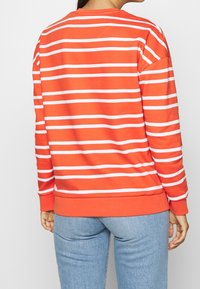 Sudadera a rayas rojas y blancas, material de algodón, cuello redondo, mangas largas, puños y dobladillo acanalados. Diseño sencillo y casual.