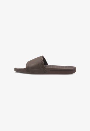 Brown rubber slide sandal with a wide strap, textured design, and horizontal grooves. Flat sole with a slightly raised heel. Lightweight construction.
