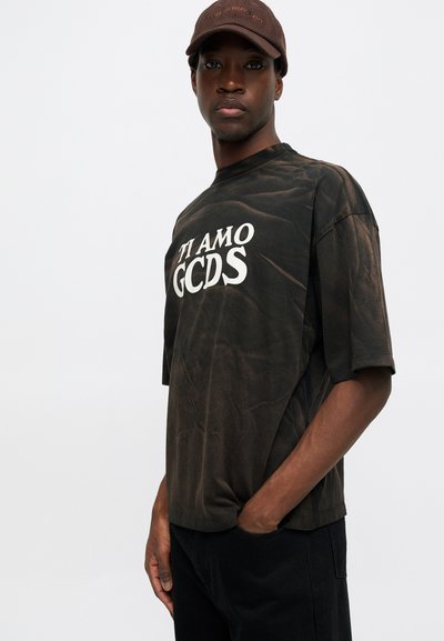 Svart, overdimensjonert T-skjorte med et slitt utseende, med hvit tekst "TI AMO GCDS" på forsiden. Korte ermer og rund hals.
