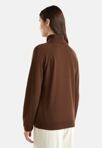 Brauner, langärmliger Pullover mit hohem Kragen, aus weichen Materialien gefertigt, mit lässiger Passform und gerippten Akzenten am Kragen und Saum.