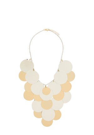 Naszyjnik z warstwowymi dużymi złotymi i beżowymi metalowymi dyskami przymocowanymi do delikatnego złotego łańcuszka z regulowanym zapięciem.