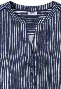 Blouse bleu marine à rayures blanches verticales irrégulières, col rond, trois boutons devant, et étiquette de marque "CECIL" à l'intérieur du col.