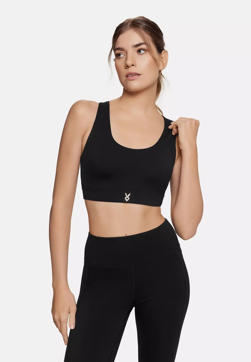 Black sports bra with wide straps, a scoop neckline, and a fitted design. Features a small silver heart logo on the elastic band.