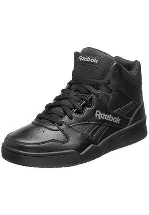 Basket Reebok montante noire en cuir texturé, languette en tissu, lacets et logo de la marque sur le côté et la languette, vue en angle sur fond blanc.