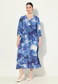 Modrá a bílá tie-dye midaxi šaty s výstřihem do V, tříčtvrtečními rukávy a elastickým pasem. Nosit s bílými vysokými podpatky.