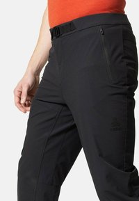 Schwarze Outdoor-Hosen mit schmaler Passform, ausgestattet mit einer Reißverschlusstasche und einem verstellbaren Gürtel. Hergestellt aus strapazierfähigem, dehnbarem Material, geeignet für verschiedene Aktivitäten.