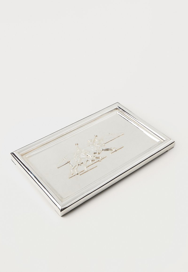 Taisnstūra formas sudraba šķīvis ar pulētu virsmu, kurā ir reljefa dizains ar jātniekiem uz zirgiem, apkārt kā mirdzošs, slīpi apgriezts mala.