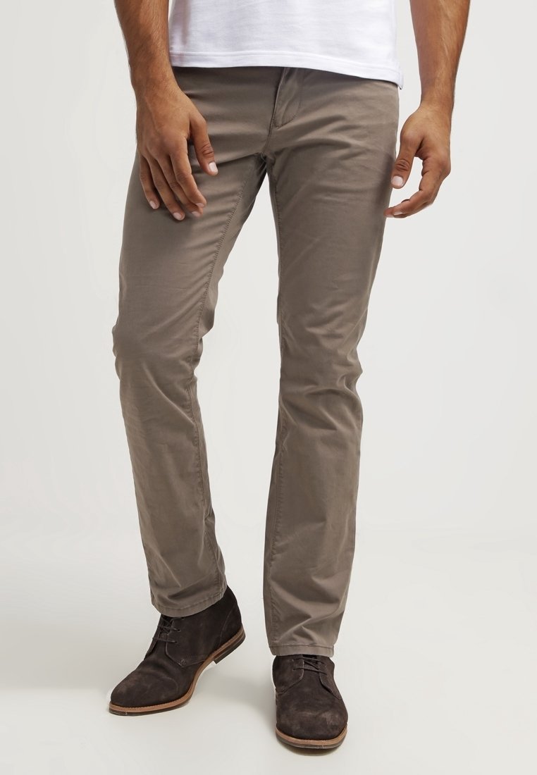 Lichtbruine katoenmix chino's met een slim fit, voorzien van subtiele stiksels, zijzakken en gedragen met donkerbruine suède enkellaarsjes.