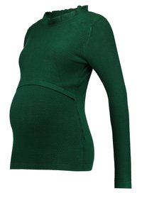 Ciemnozielony, teksturowany sweter ciążowy z długim rękawem, z falbankowym wysokim kołnierzem i detalem przy pasie na białym tle.