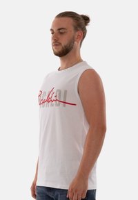 White cotton tank top featuring a red and grey graphic print. The design includes stylized text across the chest and a crew neckline.