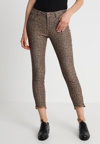 Leopardmönstrade byxor i brunt och beige, med slim fit, kort längd och fransar i nederkant. Stylar med svarta skor.