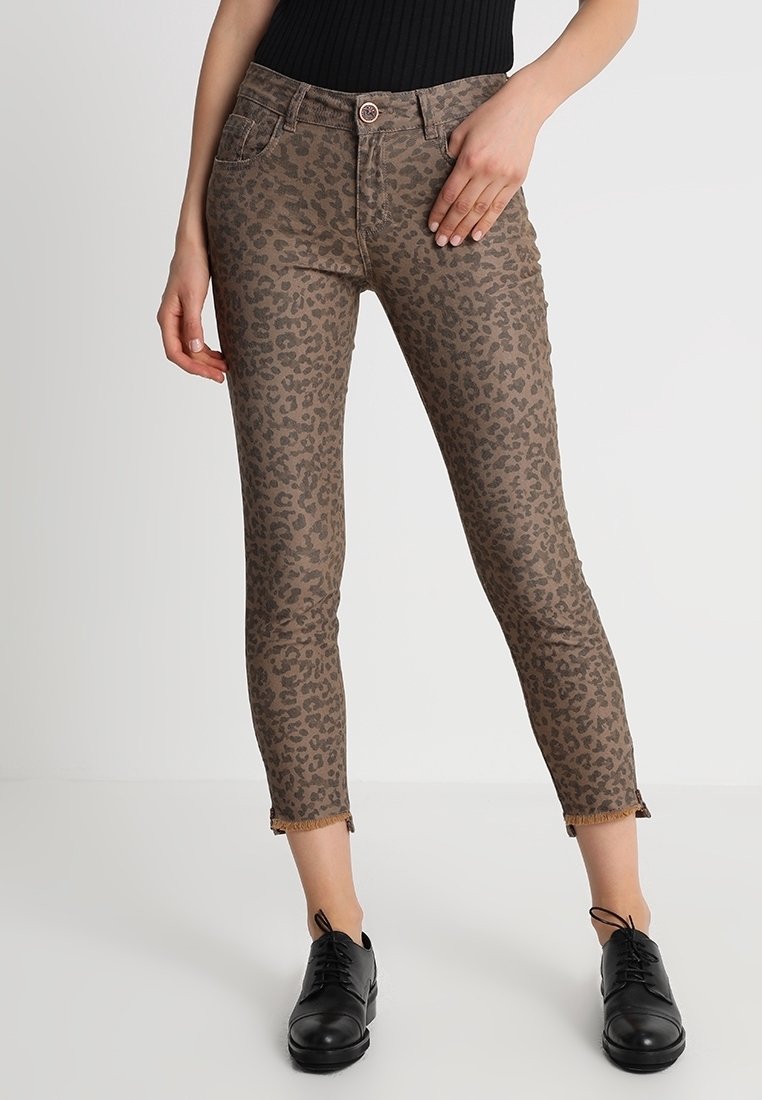 Leopardmönstrade byxor i brunt och beige, med slim fit, kort längd och fransar i nederkant. Stylar med svarta skor.