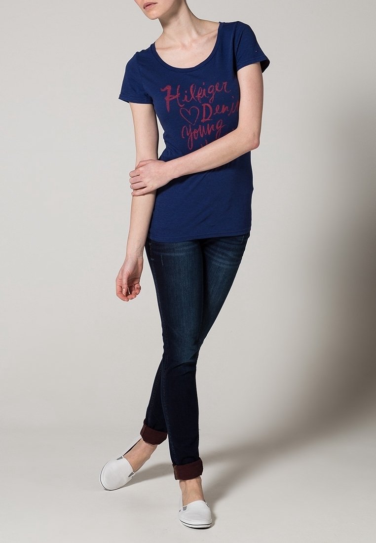 Mörkblå kortärmad t-shirt med rund halsringning och rosa text. Matchas med mörka jeans och vita slip-on skor.