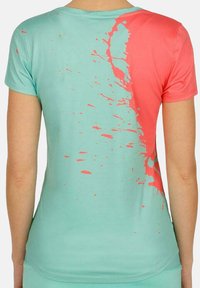 Camisa de manga corta en un tono azul claro, con un diseño abstracto de salpicaduras en coral. Tela suave con una textura lisa, silueta ajustada.
