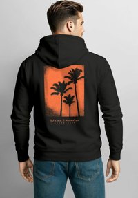 Schwarzer Hoodie mit einer strukturierten orangen Grafik von Palmen und dem Text "Bring mich ins Paradies" auf dem Rücken gedruckt. Klassische Passform, Baumwollmischung.