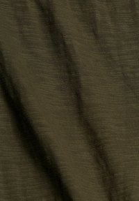 Tessuto testurizzato di un profondo verde oliva, con sottili strisce orizzontali e una qualità morbida e leggermente elasticizzata. Ideale per applicazioni di abbigliamento versatili.