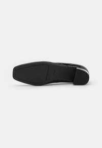 Tacco in pelle verniciata nera con forma rettangolare e superficie liscia. Presenta una punta rotonda e una suola in gomma resistente. Marchio visibile.