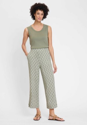 Light olive tank top paired with wide-leg patterned pants in green and cream diamond design. The model wears brown sandals.