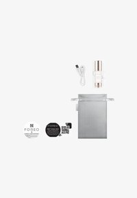 Flacon de sérum Foreo, design rond en argent et doré rose ; comprend un câble USB, une pochette de rangement grise et deux cartes de support avec des codes QR.