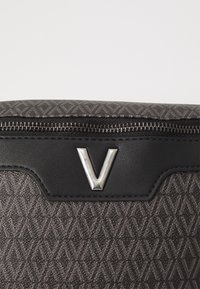 Gray textured bag featuring a diamond pattern, black leather accents, and a silver "V" logo. Zipper closure at the top.