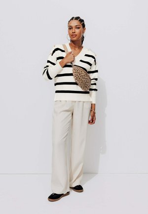 Pull rayé noir et blanc, pantalon beige et chaussures noires. Sac bandoulière avec motif léopard. Texture lisse, coupe détendue.