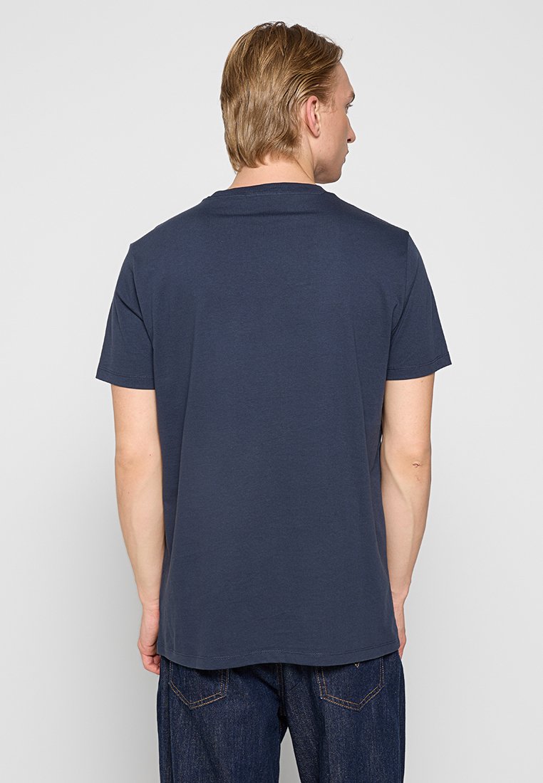 Navyblauwe T-shirt met korte mouwen en een ronde hals, gladde textuur en een rechte zoom, gedragen met donkere spijkerbroek.