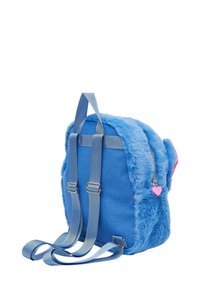 Zaino blu con texture in peluche, tessuto azzurro chiaro, spallacci regolabili, accessori in argento e dettaglio della zip a forma di cuore rosa.